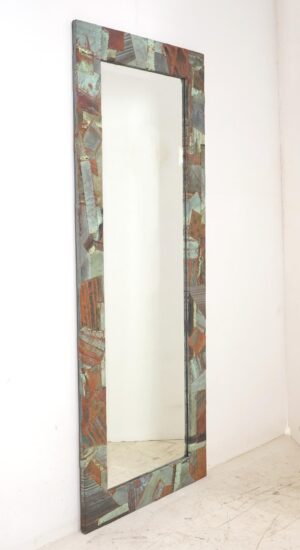 Tall dressing mirror with a handcrafted collage frame of reclaimed copper roofing in verdigris tones around a beveled mirror.