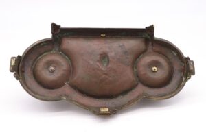 Victorian bronze desktop tray with two round inkwell wells and a raised back panel, shown from below with visible wear and mounting hardware.