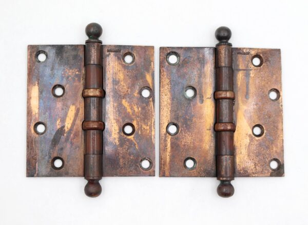 Pair of vintage door hinges with dark brass and copper-plated finish, ball tips, five knuckles, and a staggered hole pattern shown side by side.