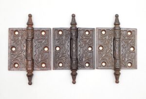 Set of three Victorian cast iron butt door hinges with steeple tips, three knuckles, and four mounting holes each, shown front-facing with visible surface wear.