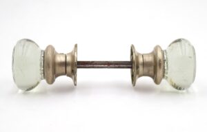 Clear glass passage door knob set with brushed nickel rosettes and a connecting spindle, shown in side view.