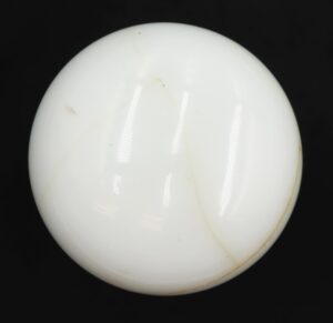 Round white milk glass dummy door knob with a subtle tan vein and a nickel-finish rosette visible in close-up.