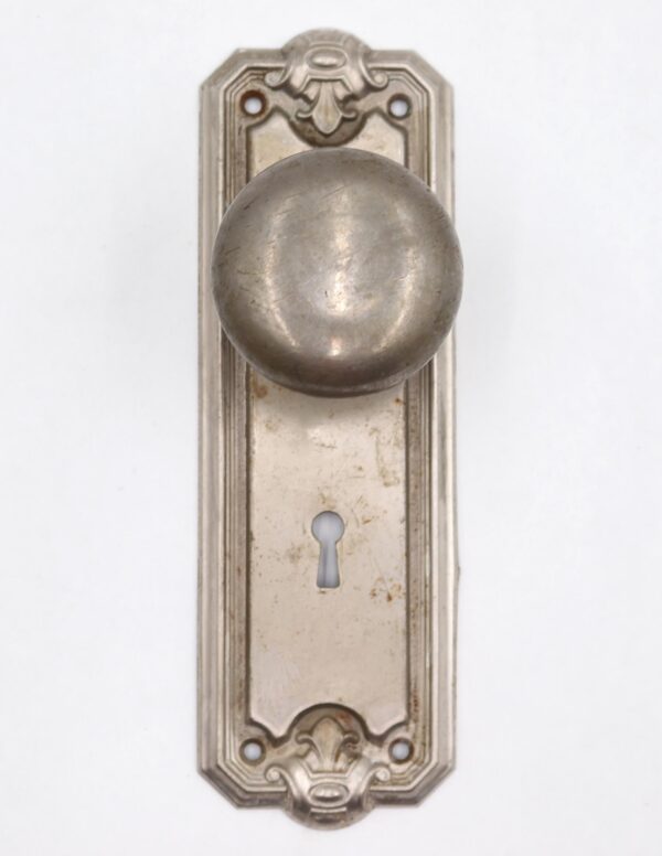 Art Deco dummy door knob set with a round brushed nickel knob, decorative back plate, and keyhole opening.