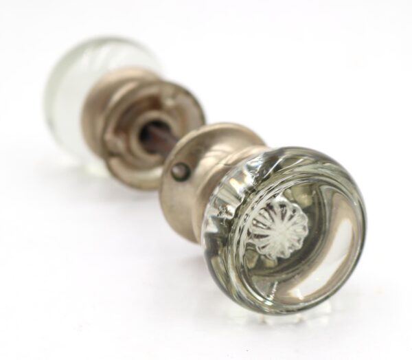 Clear glass passage door knob set with brushed nickel rosettes, shown in close-up from the end of one knob.