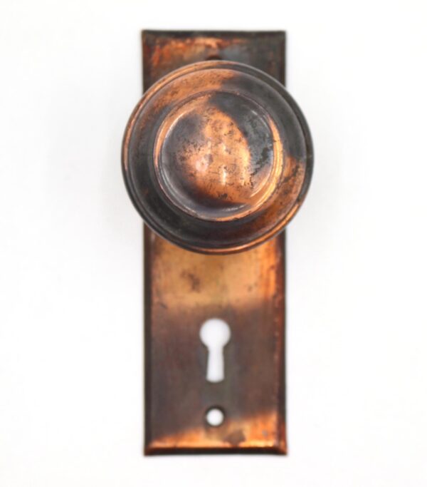Vintage dummy door knob set with a concentric knob face on a flat back plate and keyhole opening.