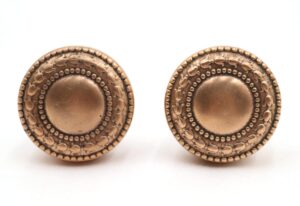Pair of Victorian brass passage door knobs shown side by side, each with a round embossed face and polished finish.