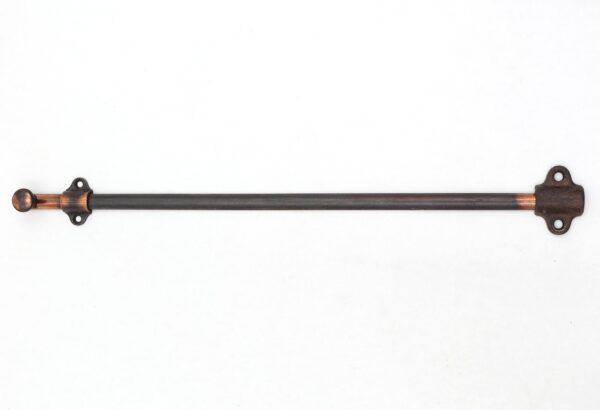 Vintage steel door surface bolt with a long black barrel, copper accents, and mounting plates at each end.