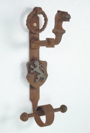 Gothic wrought iron double door pull with a central shield and ring knocker, showing heavy rust and wear.