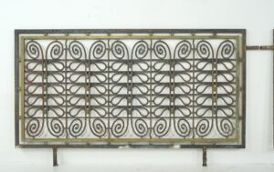 Pair of decorative architectural grills with a rectangular frame and repeating scroll pattern, shown as a side-by-side pair with surface wear and a black and brass finish.