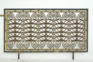 Decorative wrought iron and brass grill panel with scrollwork and vertical bars, shown front on as a rectangular architectural screen.