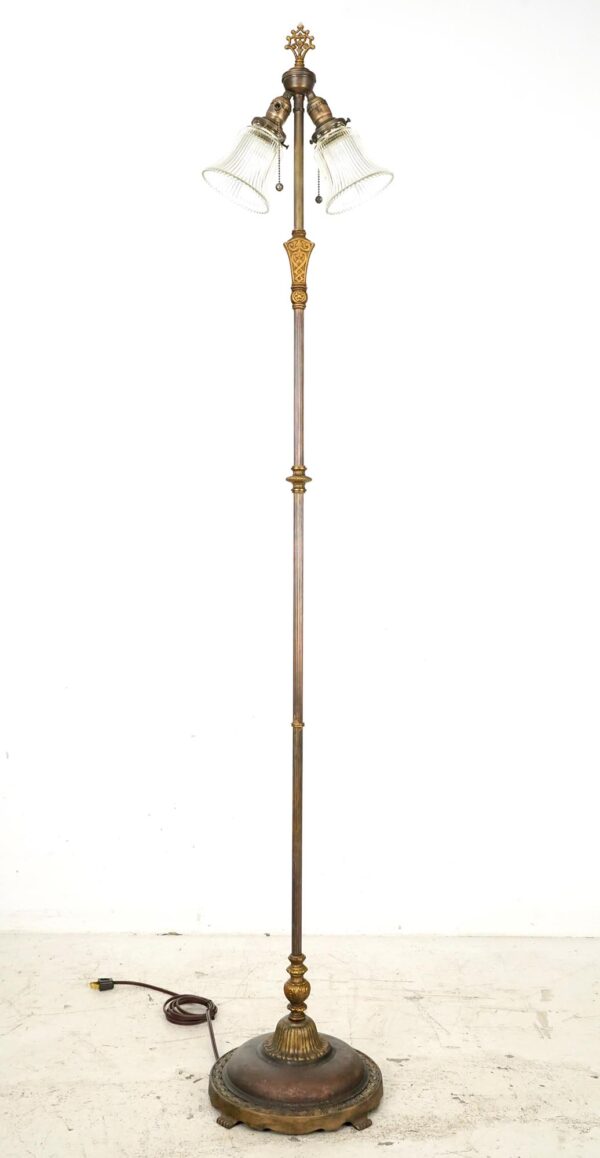 Victorian two-light floor lamp with clear ribbed glass shades, a brass pole, and an ornate cast iron base.