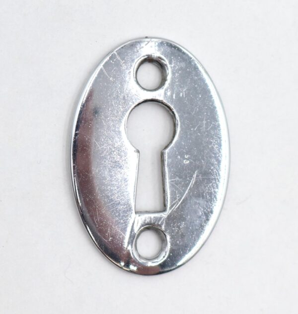 Oval chrome keyhole cover plate with two screw holes and a keyhole opening.