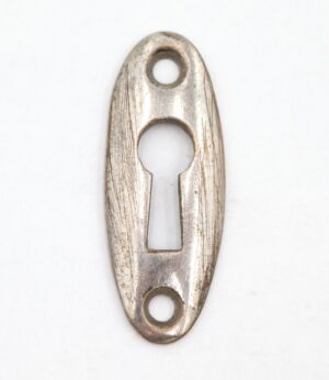 Oval keyhole cover plate with a keyhole opening and two screw holes, shown front on with visible surface wear and scratches on the nickel-finished brass.