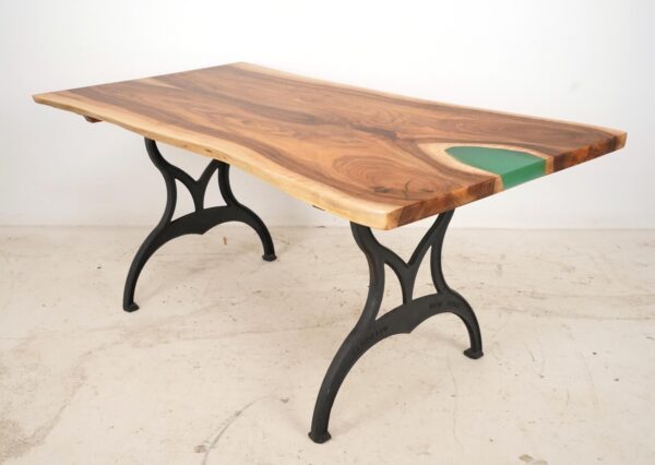 Live edge walnut dining table with a blue-green resin pour on one end and black cast iron Brooklyn legs shown at a three-quarter angle.