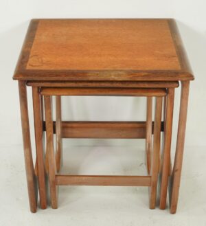Set of three mid-century nesting tables in a dark and medium wood tone, stacked together to show the top table and the smaller tables beneath it.