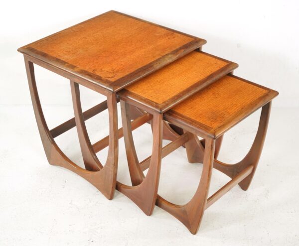 Set of three mid-century nesting tables with stepped tops and curved side supports.
