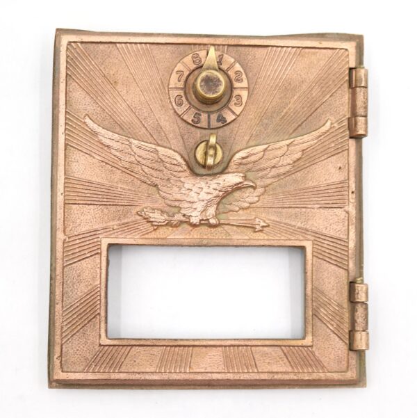 Vintage polished bronze PO box door with a flying eagle, combination dial, and empty lower window opening.