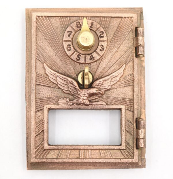 Vintage bronze PO box door with a combination dial, flying eagle relief, and an open rectangular window below.