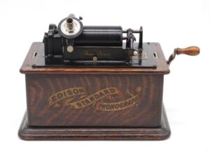 Antique Edison Standard phonograph with a hand crank, black mechanism, and dark wood base.