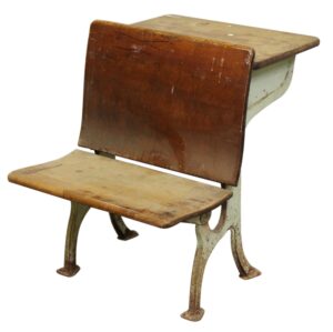 Antique tandem school desk with a dark wood seat and writing surface on a light green cast iron base, showing worn surfaces and student marks.