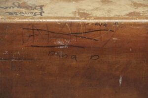 Close-up of a worn wood school desk surface with student signatures and pencil marks.