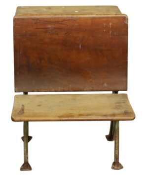 Antique cast iron tandem school desk with a dark wood seat and back, showing a worn surface and metal legs.