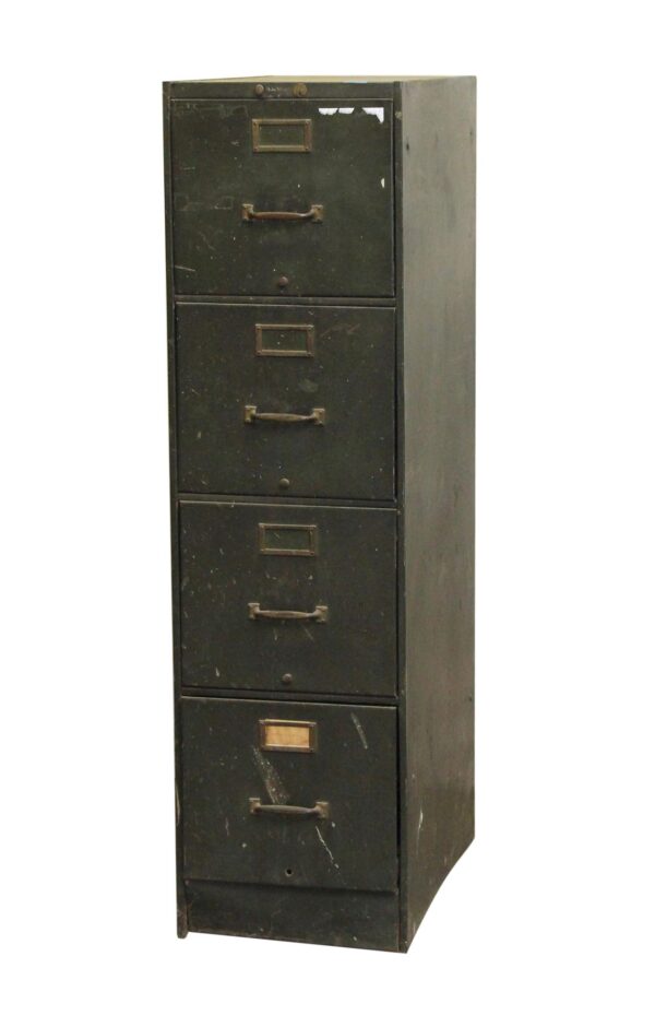 Tall green steel filing cabinet with four letter-size drawers, brass pulls and label holders, shown in a front three-quarter view with visible surface wear.