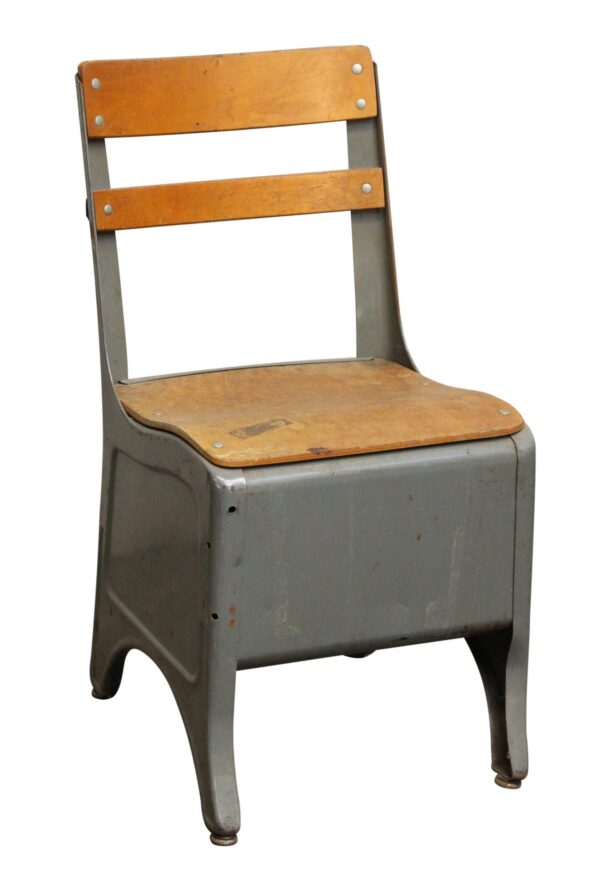 Vintage child's school chair with a steel frame, wooden seat and back, and an enclosed cubby base.
