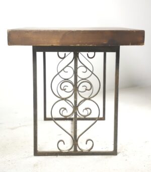 Side table with a dark wood tone pine top and a wrought iron base featuring heart and scroll motifs.