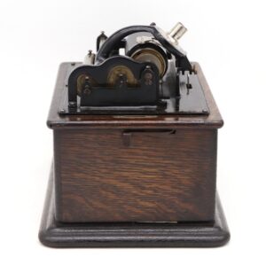 Antique phonograph with a dark wood base and exposed cast iron mechanism shown from the front.