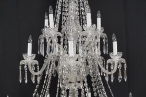 A crystal chandelier with multiple candle-style bulbs and hanging prism strands shown in close-up.