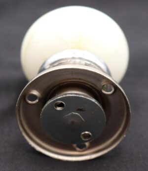 Vintage dummy door knob set with a round white milk glass knob and nickel finish brass rosette, shown in close-up from the mounting end.