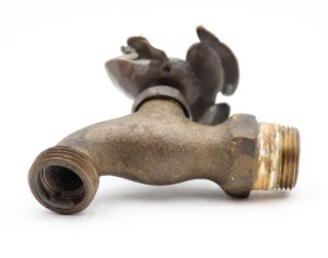 Antique brass garden spigot with a frog-shaped handle and threaded ends, shown in close-up with visible surface wear.