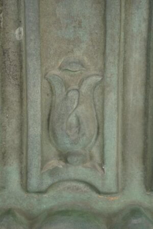 Close-up of an antique copper cornice wall art piece with verdigris patina and carved ornament detail.