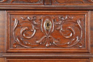 Close-up of a Victorian mahogany dresser drawer with carved relief details and original brass keyhole hardware.