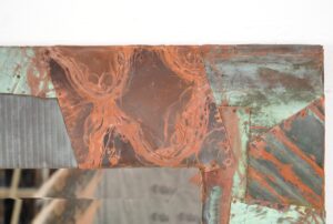 Handcrafted dressing mirror with a collage of reclaimed copper panels in copper and verdigris finish surrounding the beveled mirror edge.