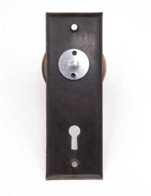 Vintage dummy door knob set with a flat black steel back plate, a round silver mounting disc near the top, and a keyhole cutout in the center.