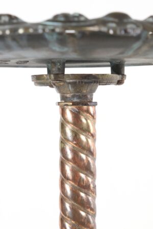 Close-up of the Victorian brass plant stand showing the scalloped top support and twisted central column with aged surface wear and tarnish.