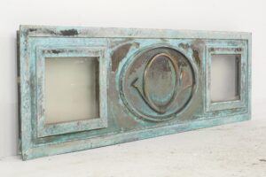 Decorative window panel with a verdigris finish, featuring two clear side panes and a raised post horn relief in the center.