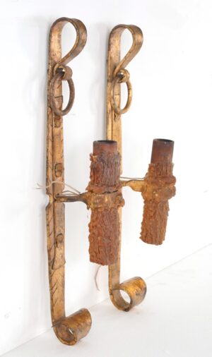 Pair of Spanish Revival wrought iron wall sconces with scrollwork arms and textured candle sleeves.