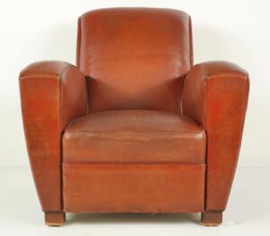Brown leather club chair with a square back, cigar-style armrests, and block feet, shown from the front with visible wear.
