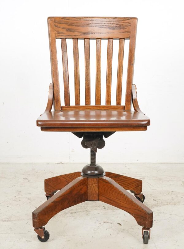 Antique swivel desk chair with a vertical slatted back, contoured seat, and star base on casters.
