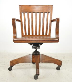 Antique swivel office chair in dark wood tone with slatted back, curved armrests, and a cast iron base on casters.