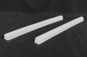 Pair of white glazed ceramic pencil wall tiles shown as two rounded strips, one slightly closer to the camera than the other.