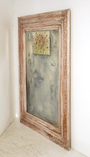 Handmade wall mirror with a carved wood frame, distressed silvered glass, and a small floral photograph at the top.