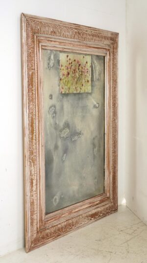 Large wall mirror with an ornate wood frame and a small floral photograph at the top.