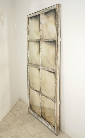 Tall wall mirror made from a reclaimed window frame with eight panes and a circular detail near the top.