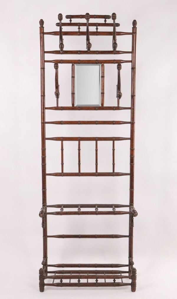 Victorian hall tree in a dark wood tone with turned bamboo-style detailing and a beveled mirror at the center.