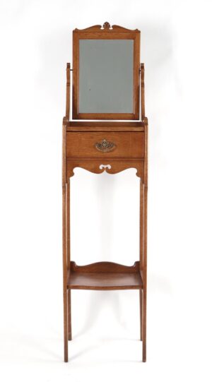 Victorian oak shaving stand with a beveled mirror, single drawer, ornate brass pull, and open lower shelf.