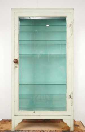 Vintage steel glass cabinet with a white exterior, blue interior, glass door panels, a round knob, and visible wear on the frame.
